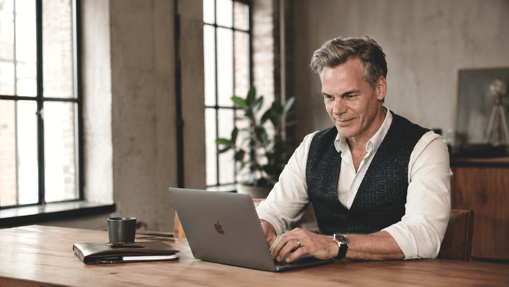 Jörn Boysen von BOYSEN & BRANDS arbeitet am Laptop in einem hellen Loftbüro – Leistungen für Markenberatung, Marketingstrategie, Kommunikation und Vertrieb.